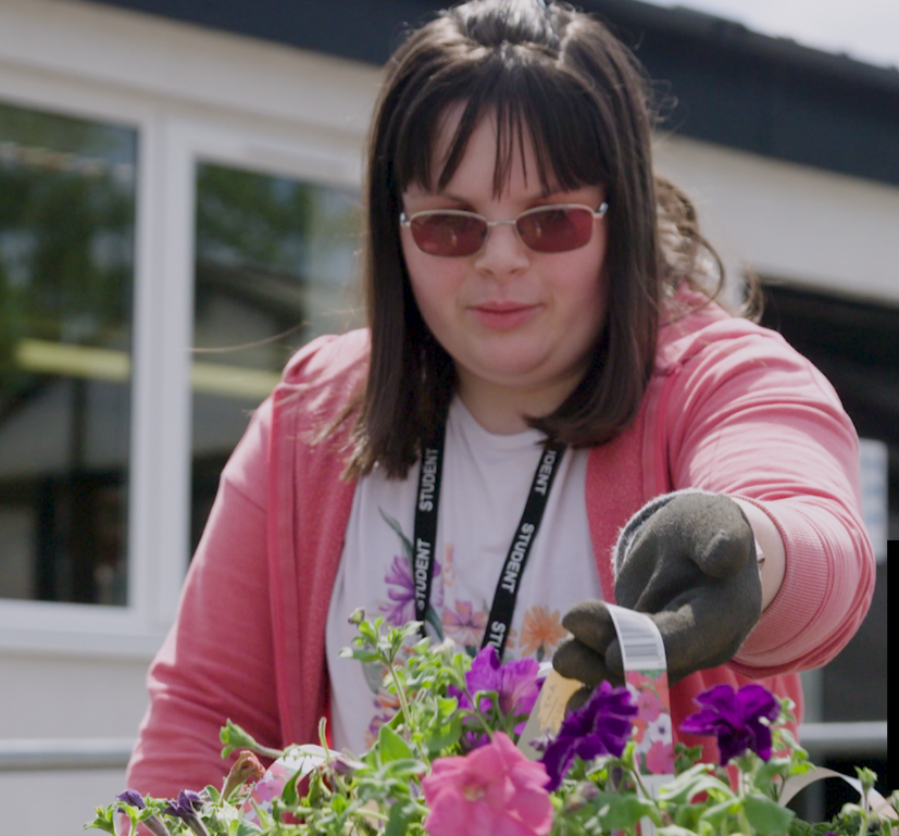 A young woman with learning disabilities planting patio plants